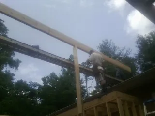 Carpenter setting a ridge beam over a new addition frame — Ice Dam Removal by Roofing Brothers in Maceo