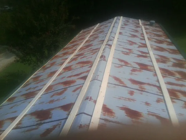 Rusted metal roof panels with new wood purlins before replacement — Storm Damage Roof Repair in Maceo by Roofing Brothers