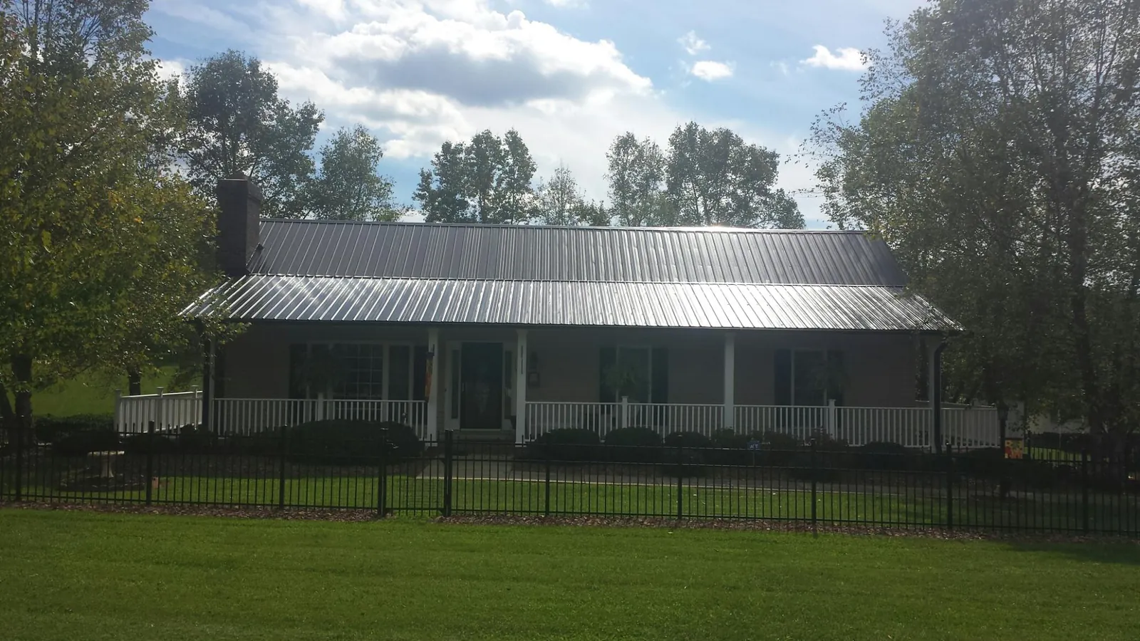 Gray metal roof on a brick ranch with a full width front porch — Gutter Guard Installation work by our crew in Maceo