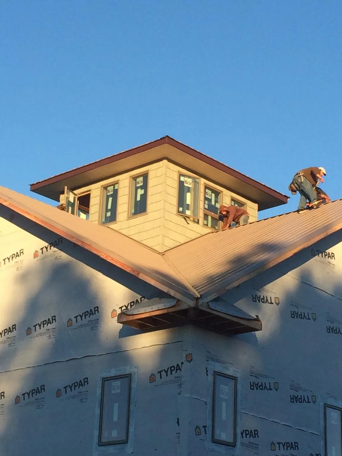 Roofers working around a rooftop cupola on a new metal roof at sunset — Roof Waterproofing in Maceo by Roofing Brothers